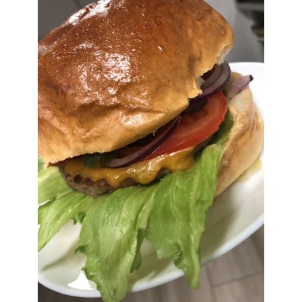 Sajtburger (Szezámos buci, marhahús pogácsa, saláta, hagyma, paradicsom, savanyú uborka, hambiszósz, cheddar sajt)